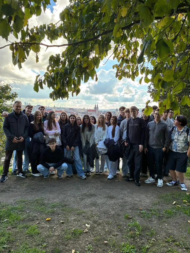 Gruppenfoto der Reisegruppe der HAK Gmunden über den Dächern von Prag, im Hintergrund die Türme der Teynkirche.